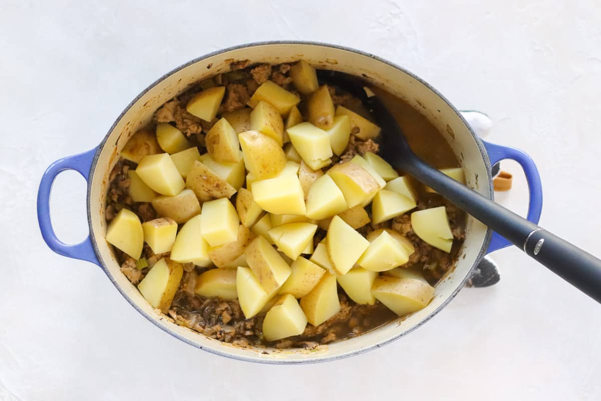 blue dutch oven with ground turkey and mushroom hash topped with boiled yellow potatoes