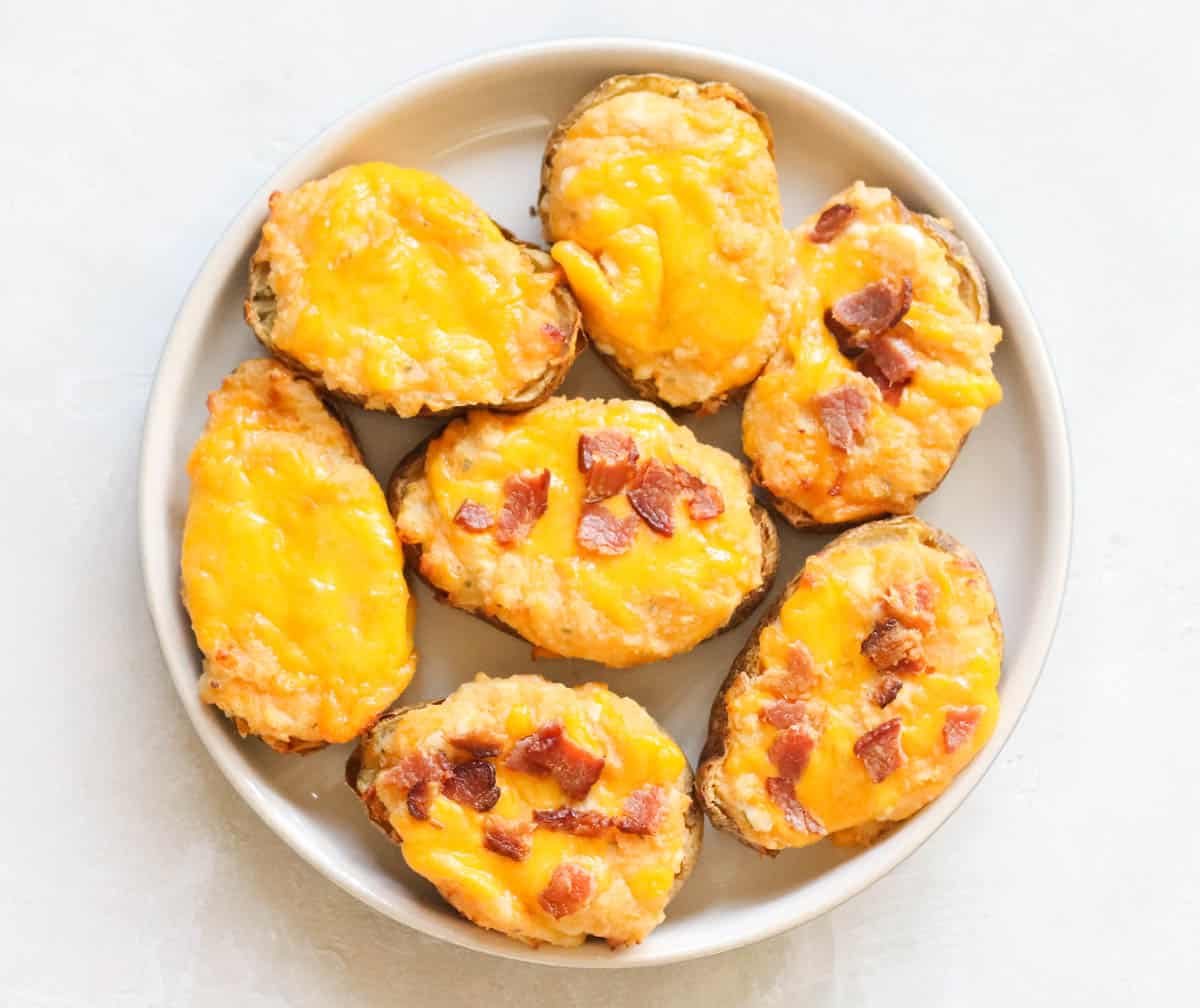 cream colored plate with three plain twice baked potatoes and four topped with bacon