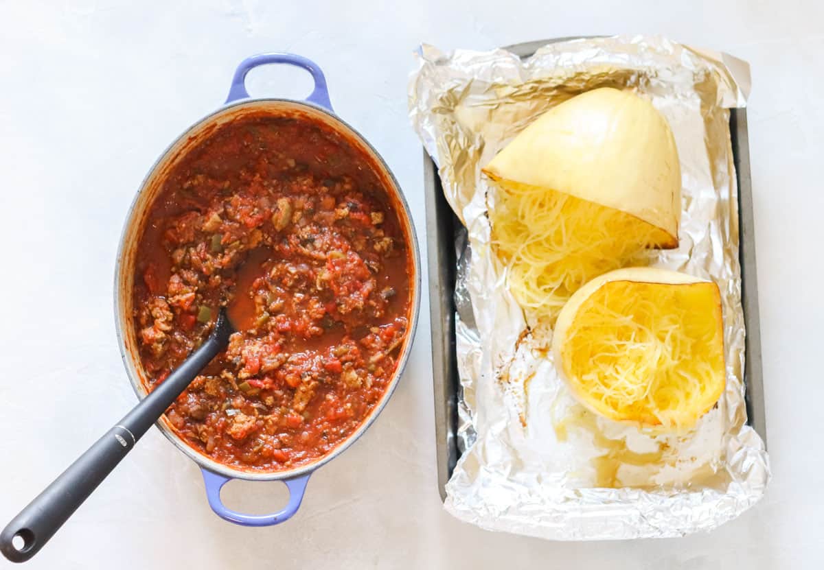 pot of prepared turkey meat sauce next to a baking dish with cooked spaghetti squash