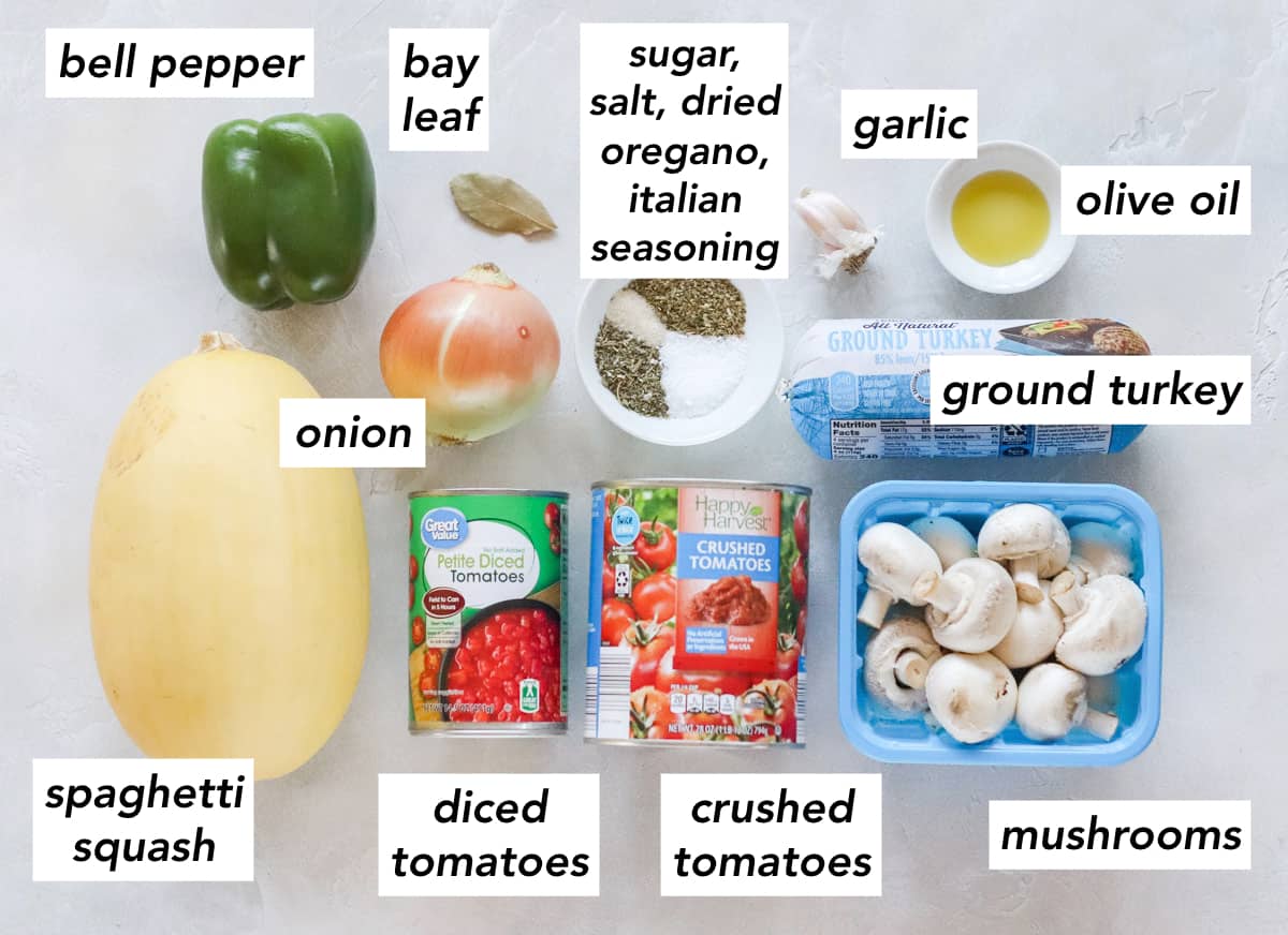 spaghetti squash, can of diced tomatoes, can of crushed tomatoes, carton of button mushrooms, package of ground turkey, bowl of olive oil, garlic cloves, bowl of salt, sugar, italian seasoning and oregano, bay leaf, green bell pepper