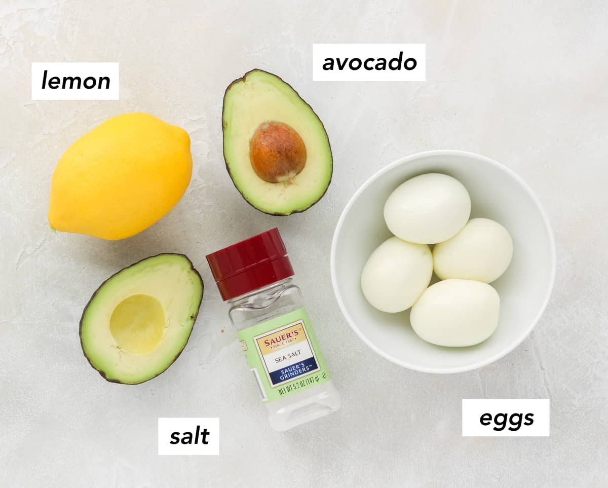 lemon, cut avocado, bottle of salt, bowl of hard boiled eggs.