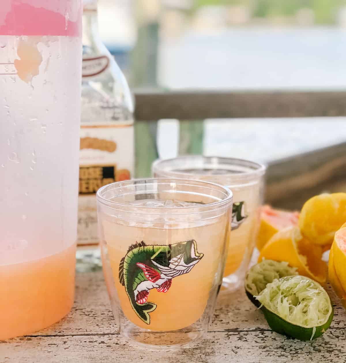 pitcher of grapefruit margaritas, bottle of tequila, glasses of pink margaritas, limes and lemons.