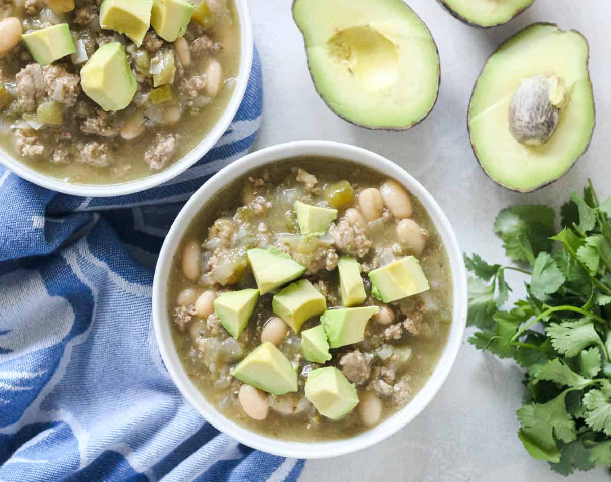 cut avocado, fresh cilantro, bowls of chili topped with fresh avocado.