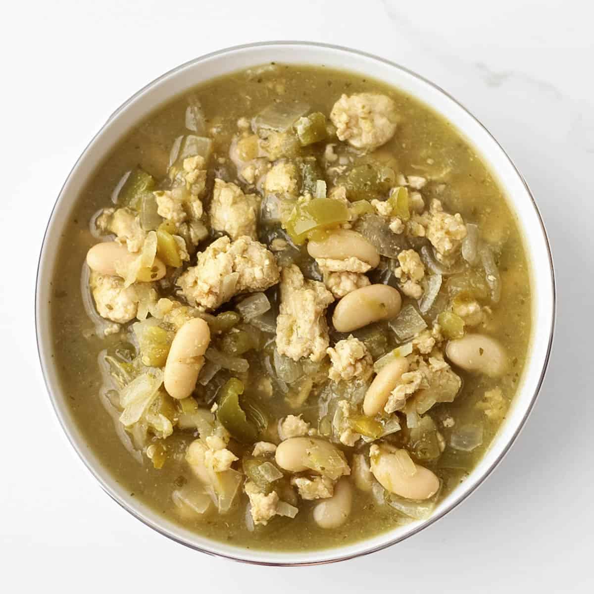 white bowl of white bean turkey chili on white counter.