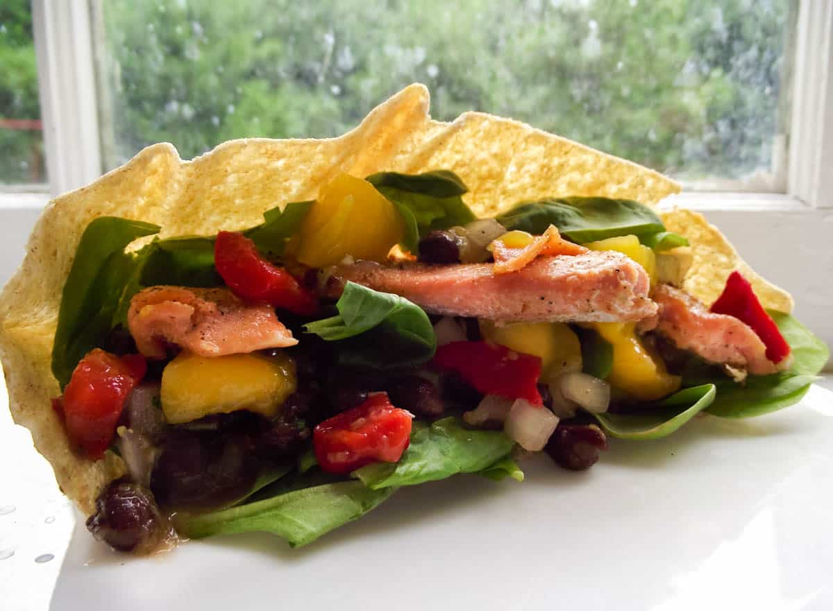 close up photo of a pita filled with salmon, spinach, and mango black bean salsa.