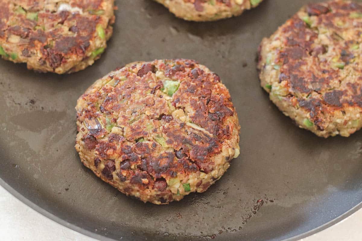 black skillet with southwestern black bean burger cooking on it.