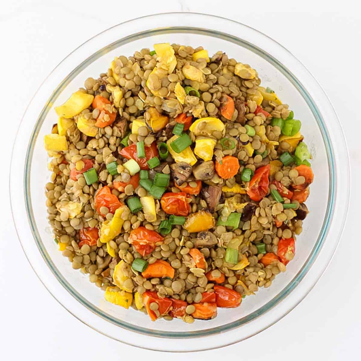 glass bowl with roasted veggies stirred into cooked lentils.
