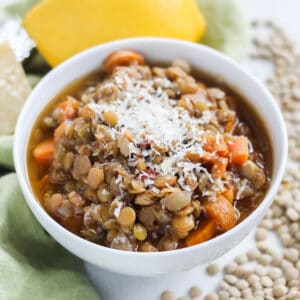 white bowl with lentil soup topped with cheese.