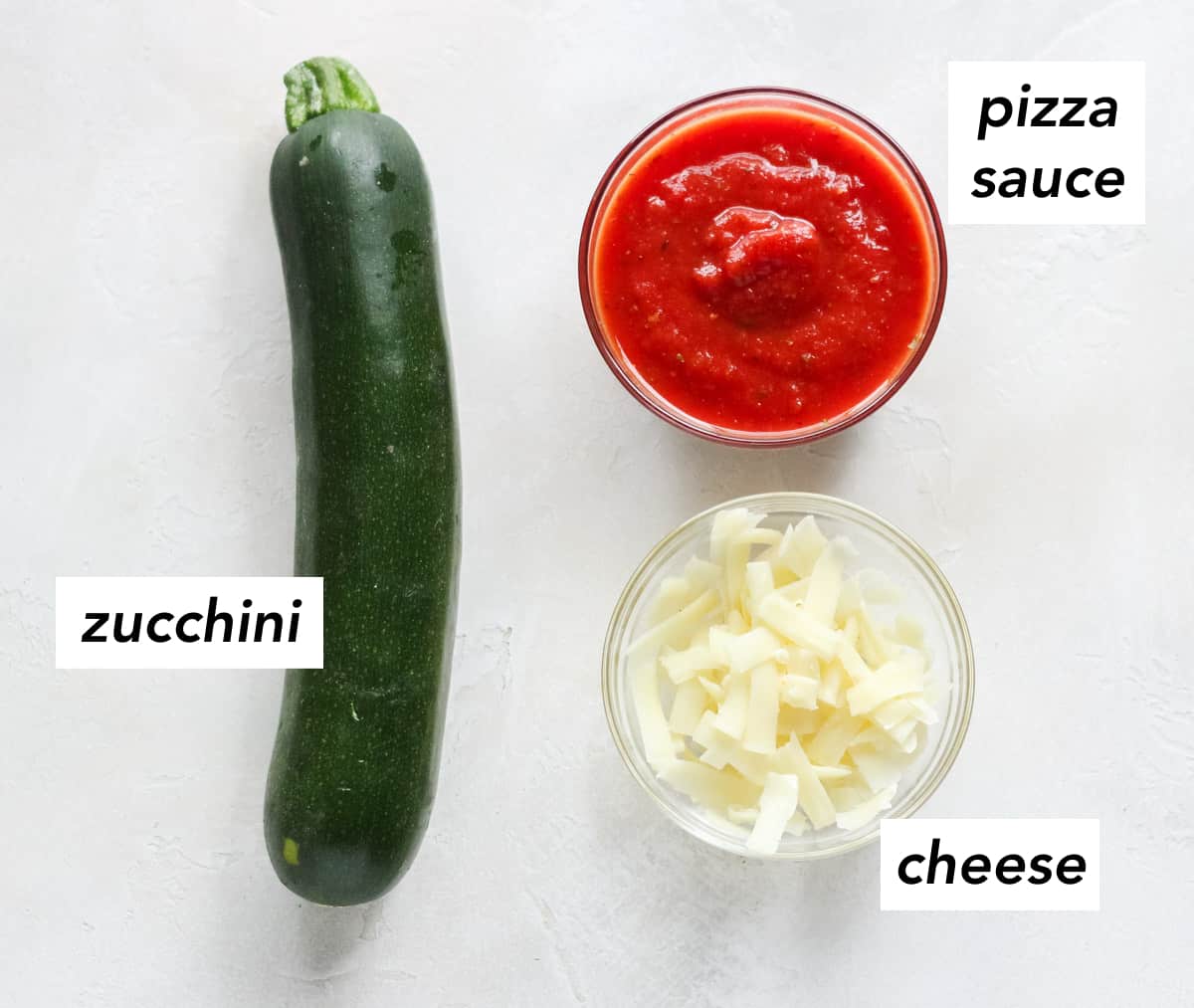 zucchini, bowl of shredded cheese, bowl of pizza sauce with text overlay describing ingredients.