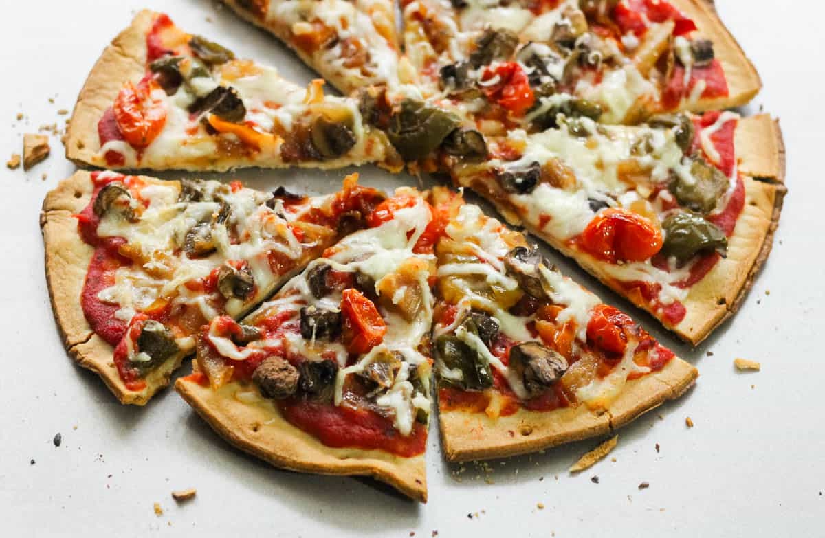 baking sheet with a baked and sliced roasted vegetable pizza.