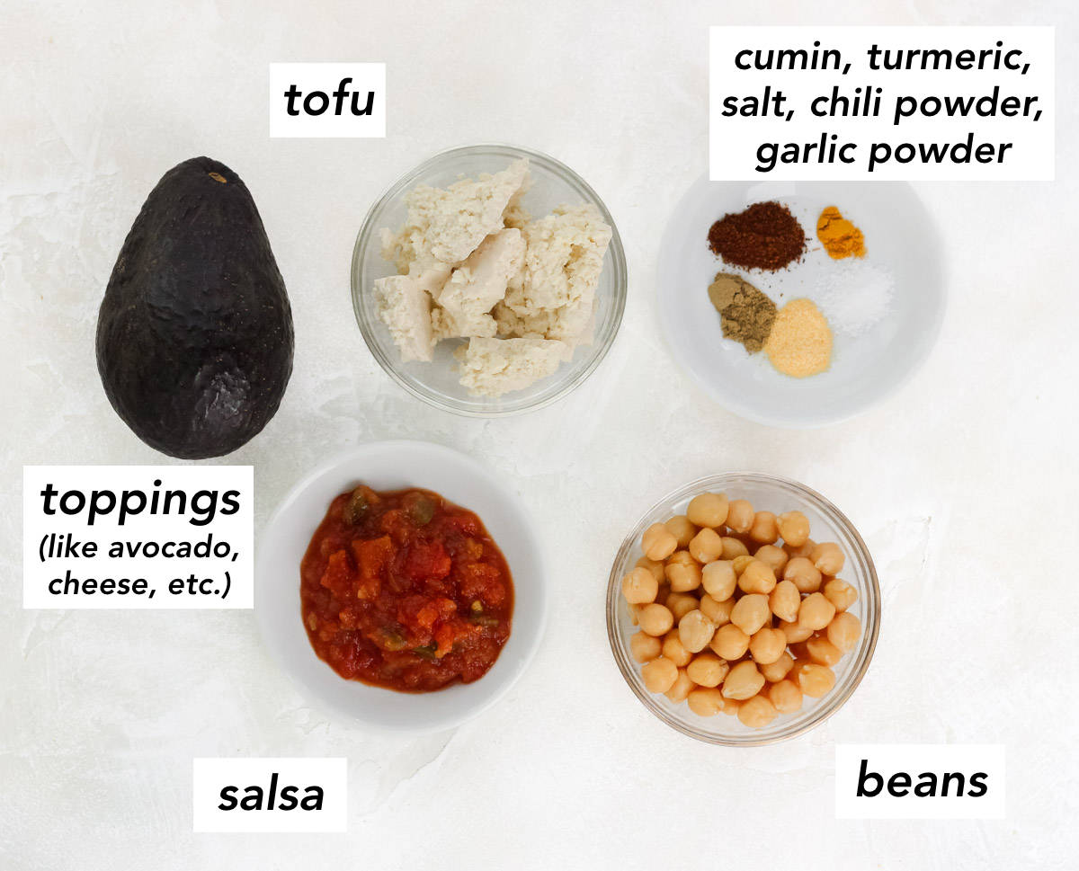 avocado, bowl of salsa, bowl of chickpeas, bowl of spices, bowl of crumbled tofu with text overlay describing ingredients.
