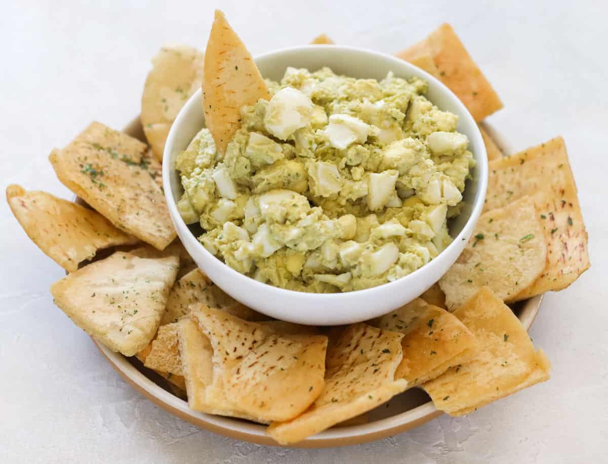 plate of pita chips with a bowl of egg salad hummus.