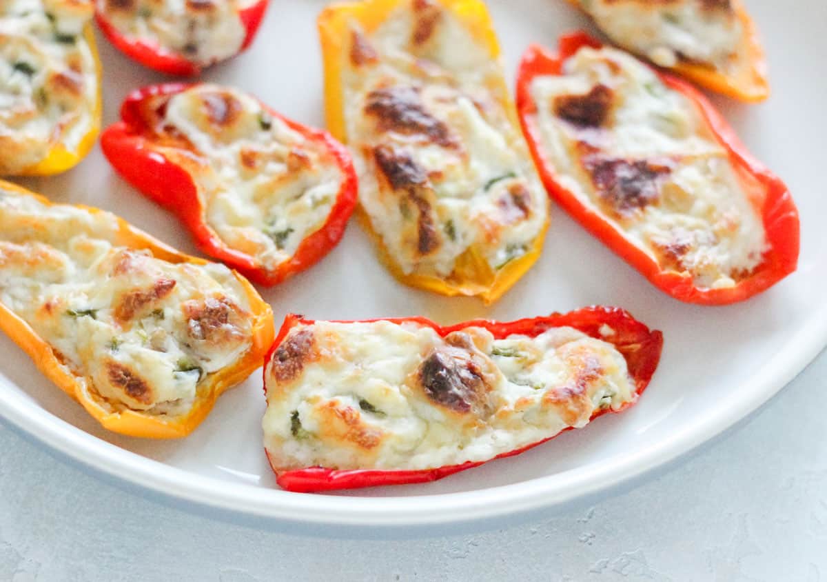 close view of a plate with baked baby bell peppers stuffed with cream cheese.