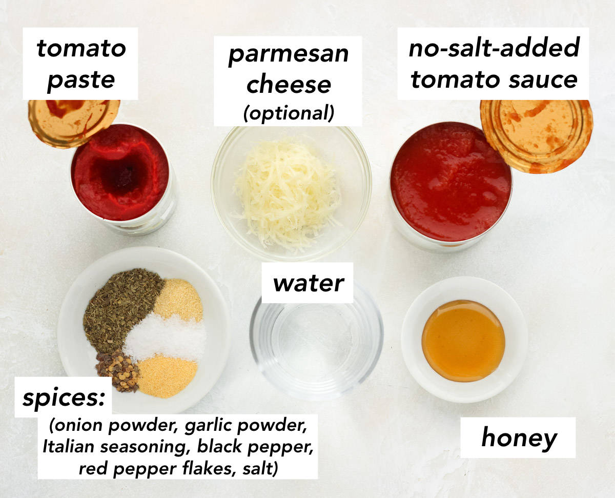 can of tomato paste, bowl of grated parmesan, can of tomato sauce, bowl of spices, cup of water, and a bowl of honey on a white counter with text overlay describing each ingredient.