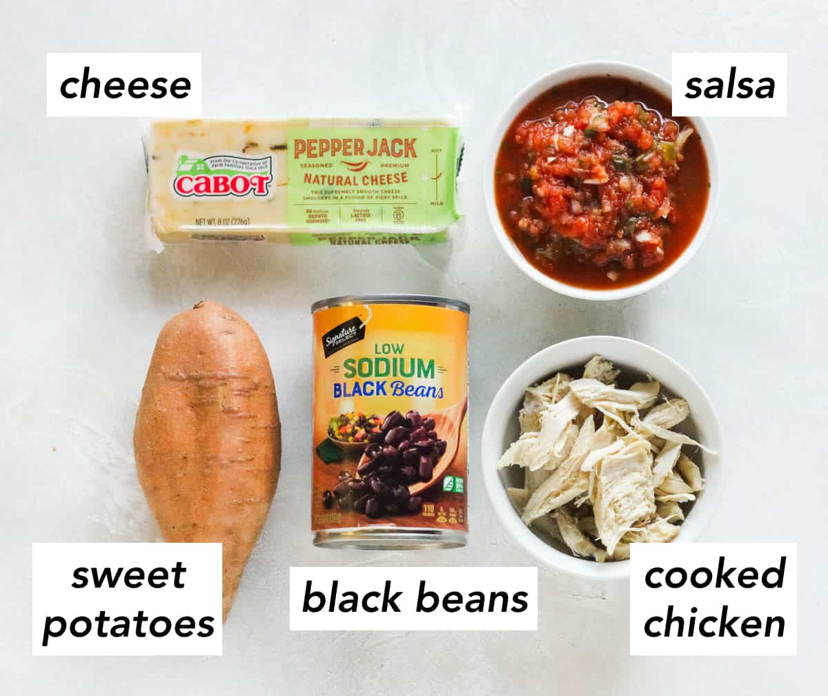 block of cheese, bowl of salsa, bowl of cooked chicken, can of black beans, sweet potatoes on white counter.