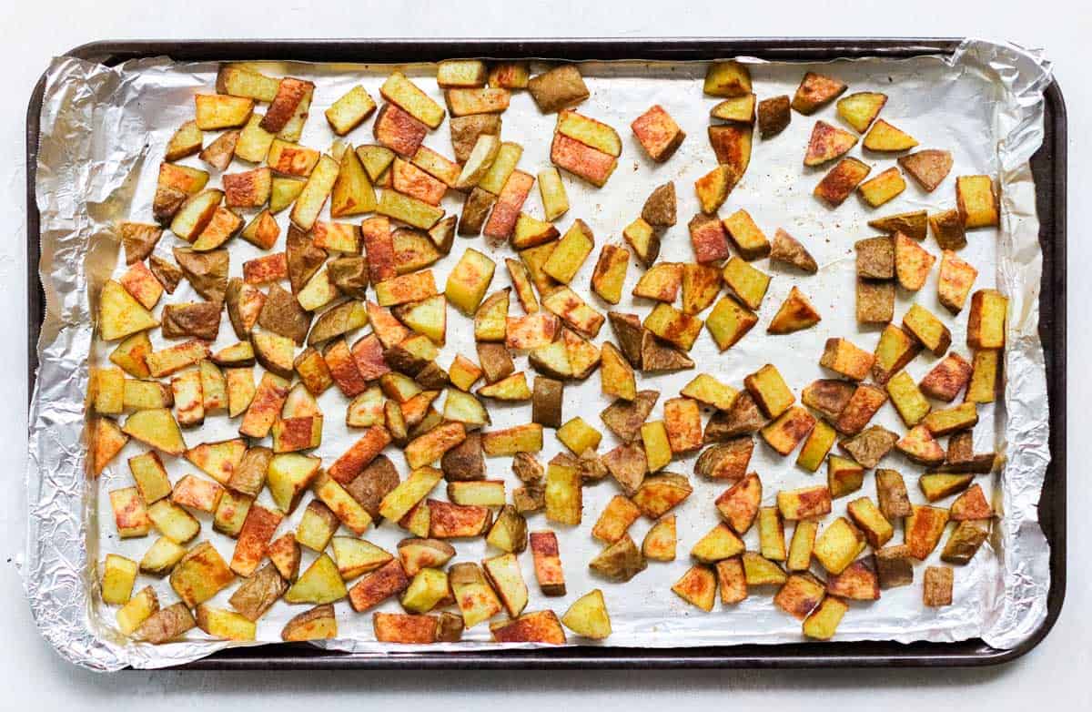 foil-lined baking sheet with roasted curry potatoes.