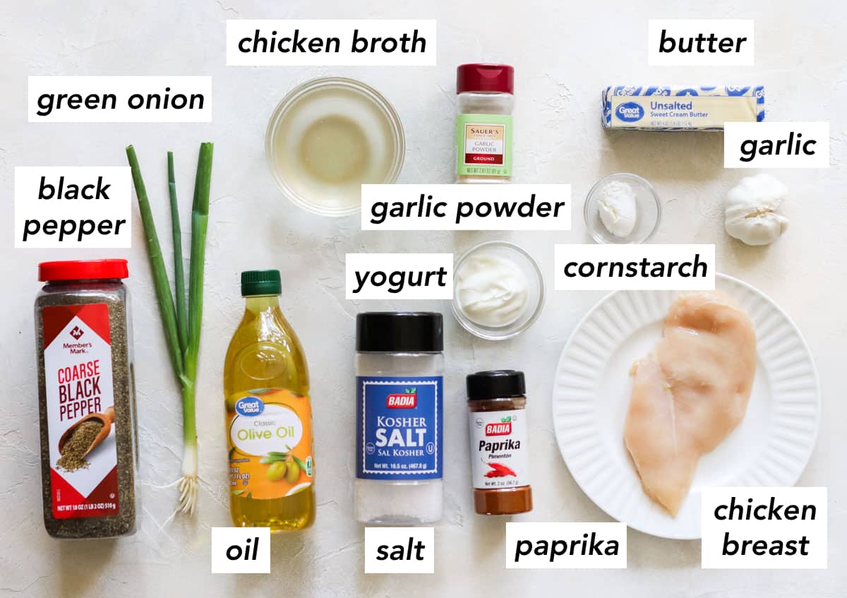 black pepper, green onion, bottle of oil, bowl of chicken broth, garlic powder, salt, paprika, plate with a chicken breast, bowl of yogurt, bowl of cornstarch, head of garlic, stick of butter with text overlay.