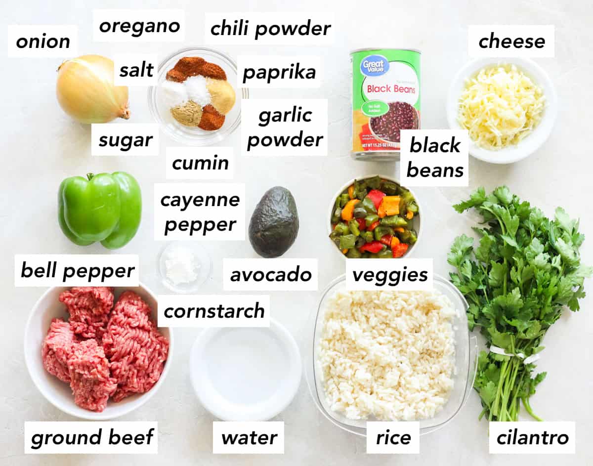 yellow onion, green bell pepper, bowl of ground beef, bowl of water, bowl of cornstarch, bowl of spices, fresh avocado, container of cooked rice, bowl of roasted bell peppers, can of black beans, bowl of cheese, and fresh cilantro with text overlay describing ingredients.
