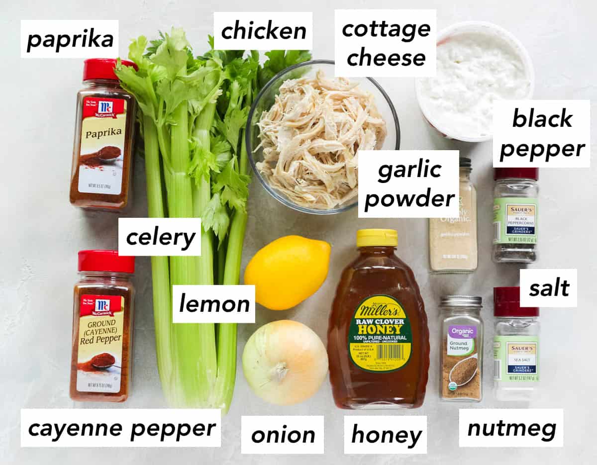 white counter with paprika, celery, chicken, cottage cheese, black pepper, salt, honey, nutmeg, garlic powder, lemon, onion, cayenne pepper.