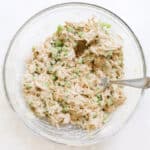 bowl of chicken salad stirred together with a silver fork.