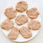 white plate with raw breakfast sausage patties before cooking.