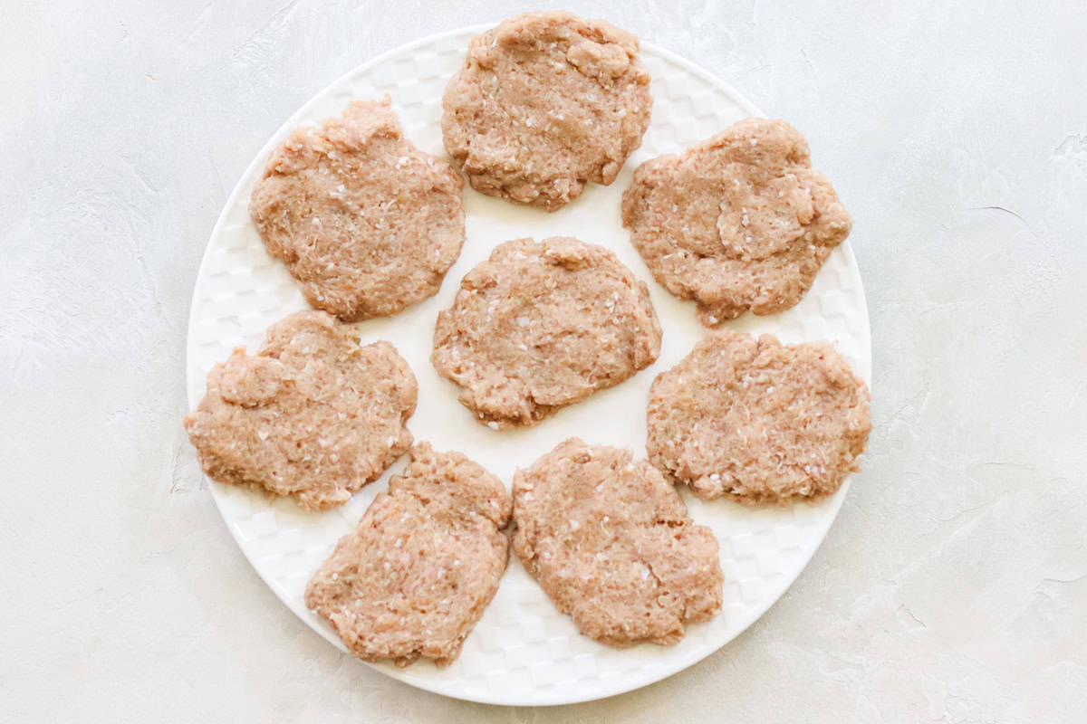 white plate with raw breakfast sausage patties before cooking.