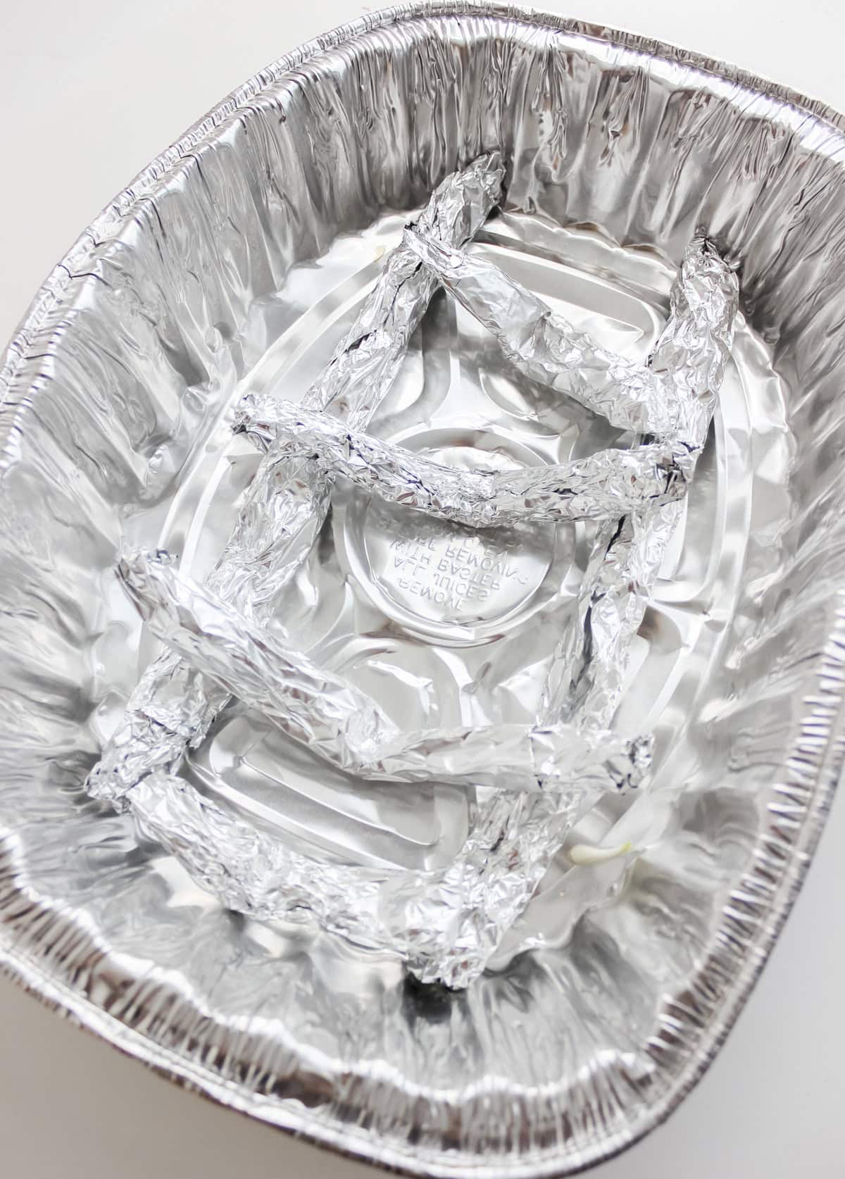 DIY roasting rack made of aluminum foil on white countertop.