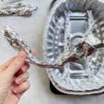 hand holding a piece of rolled foil over a DIY roasting rack.
