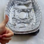 DIY roasting rack made from aluminum foil on a baking sheet with a white hand giving a thumbs up.