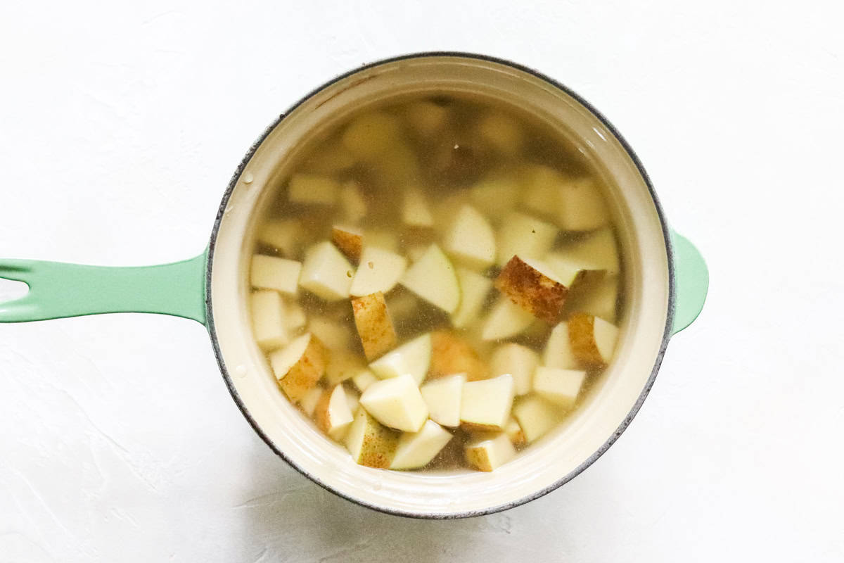 light green pot with chopped potatoes cooking in chicken broth.