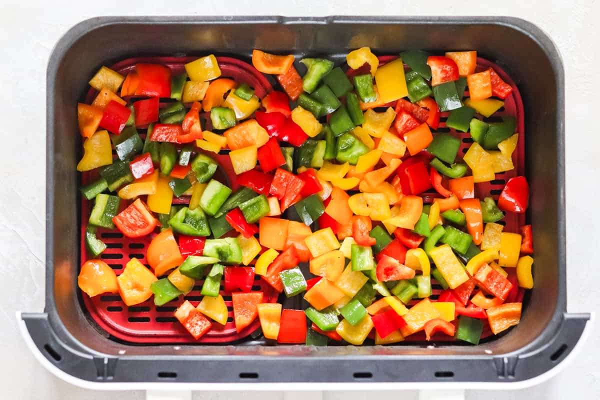air fryer basket filled with chopped bell peppers.