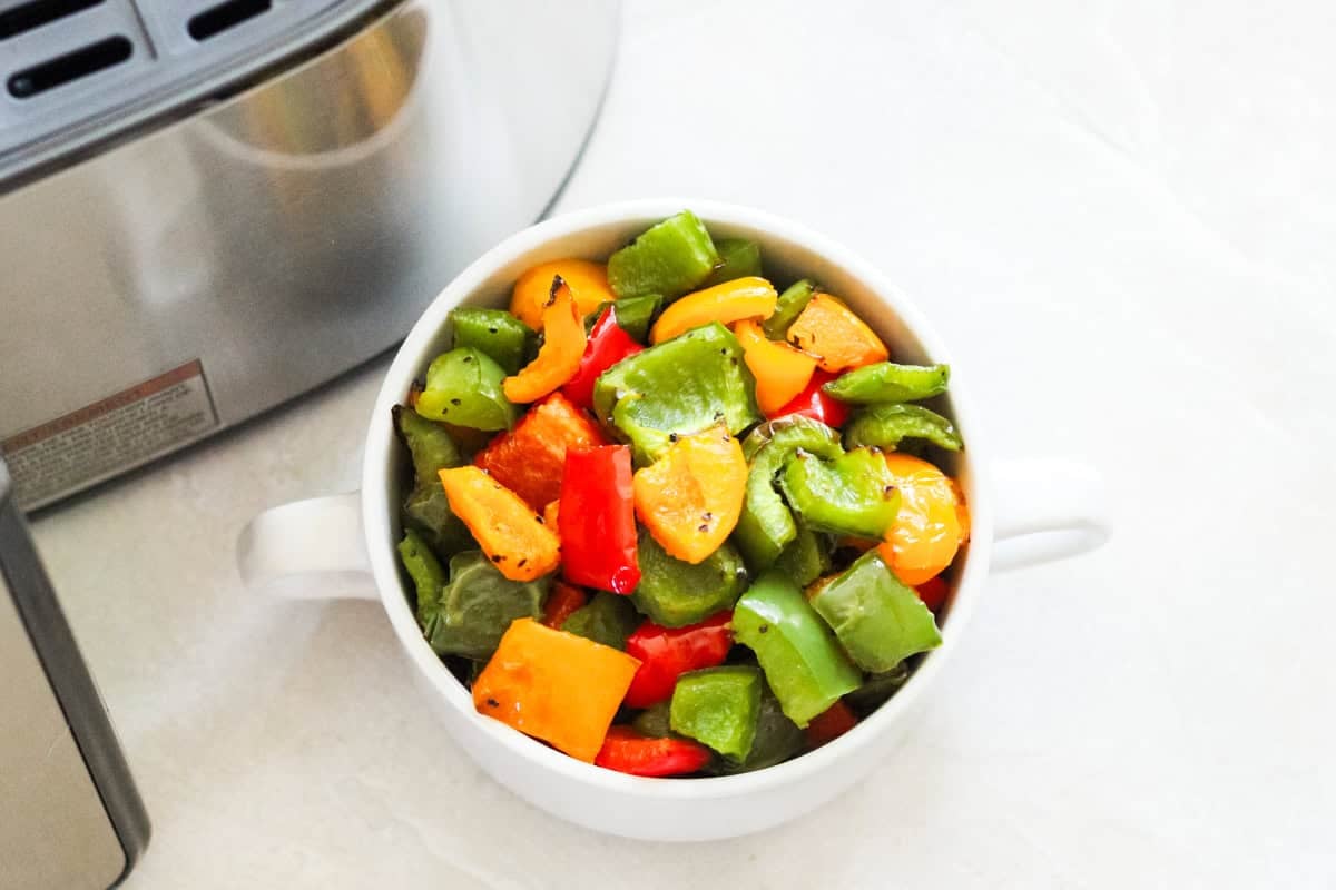 bowl of roasted bell peppers next to an air fryer.