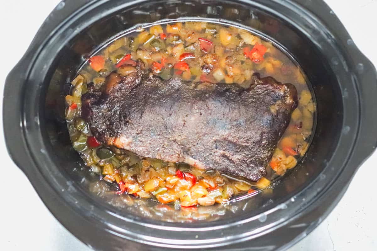 cooked flank steak in a slow cooker for beef carnitas.
