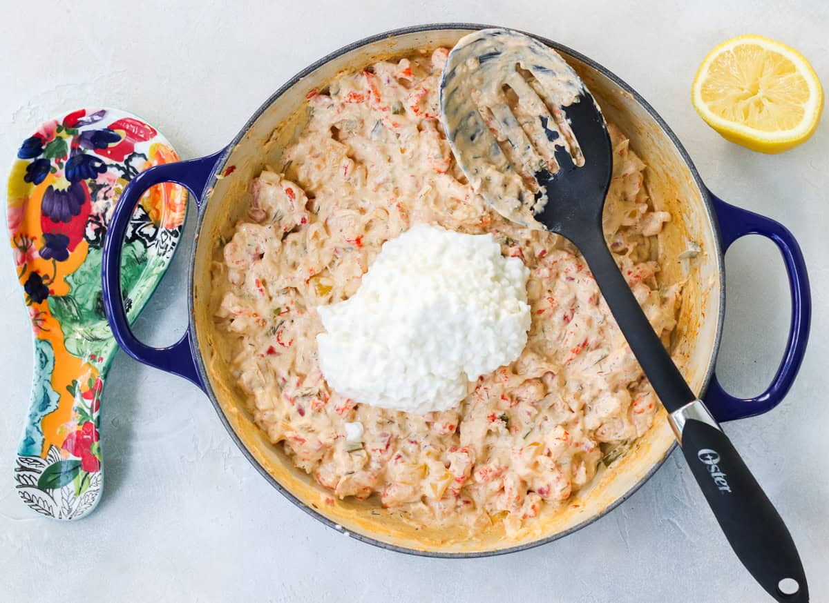 spoon rest and blue pan with crawfish dip and cottage cheese with slotted spoon.