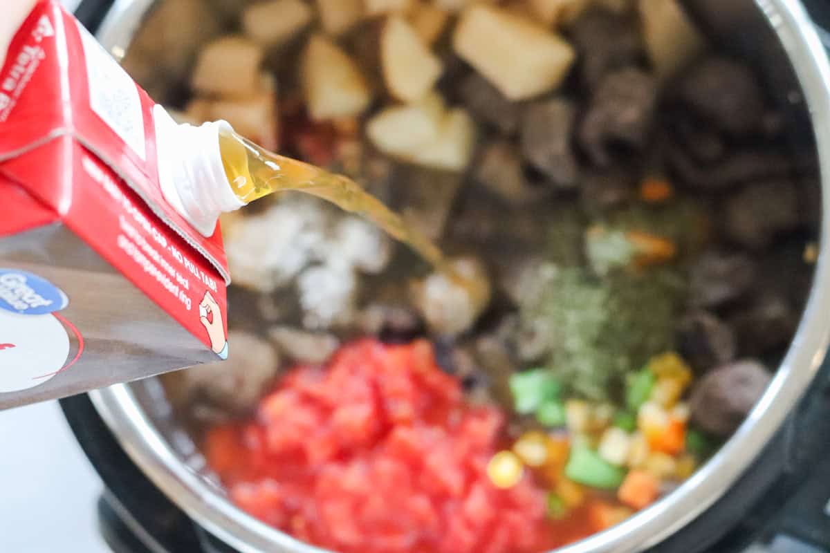 beef broth being poured into an instant pot to make beef vegetable soup.