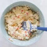 blue mixing bowl with cottage cheese and blue spatula.