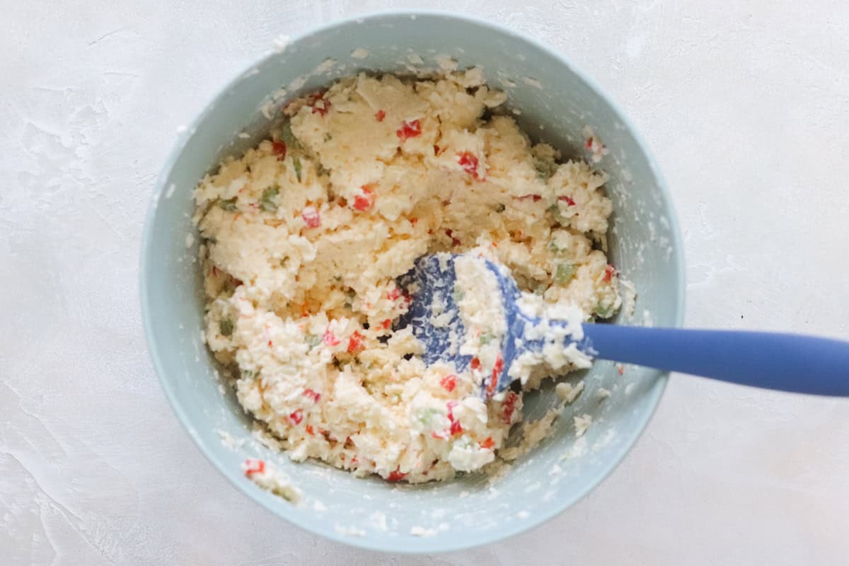 blue mixing bowl with cottage cheese and blue spatula.