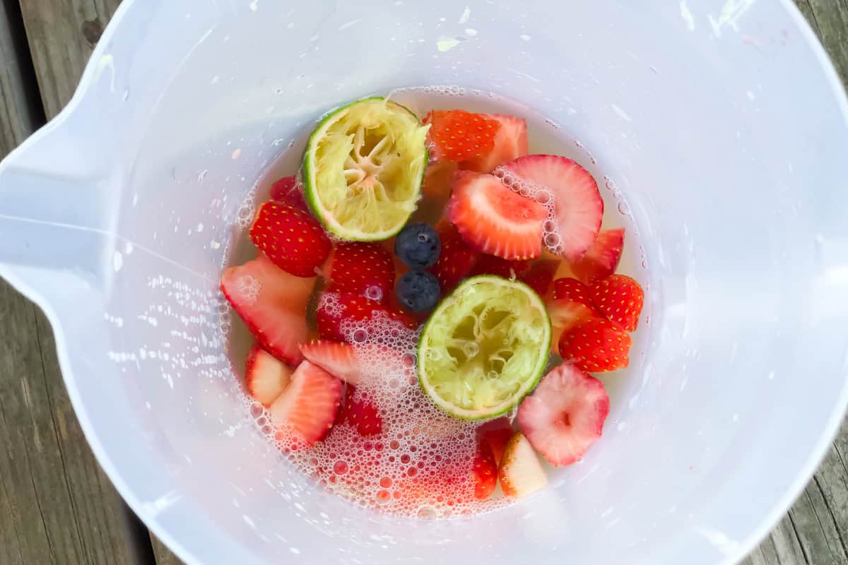 pitcher with blueberries, sliced fruit, and lime halves with white wine.