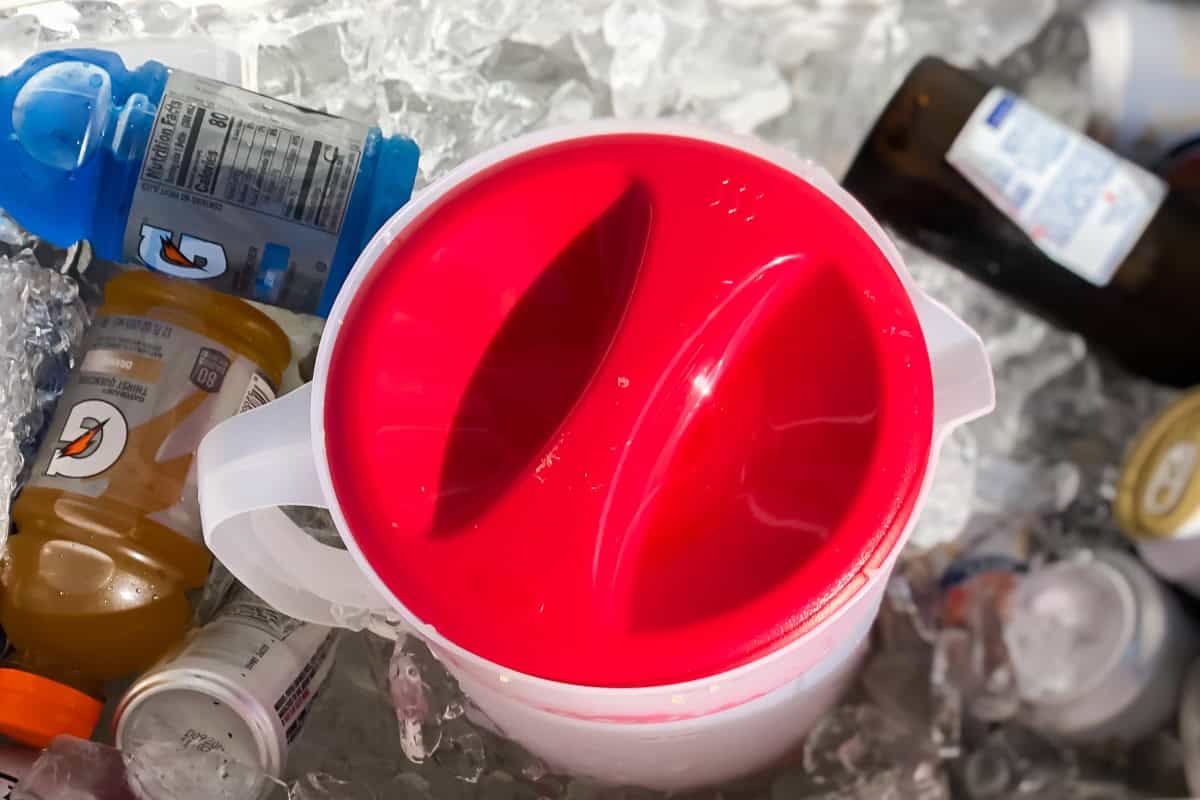 pitcher with a red top in a cooler filled with drinks and ice.