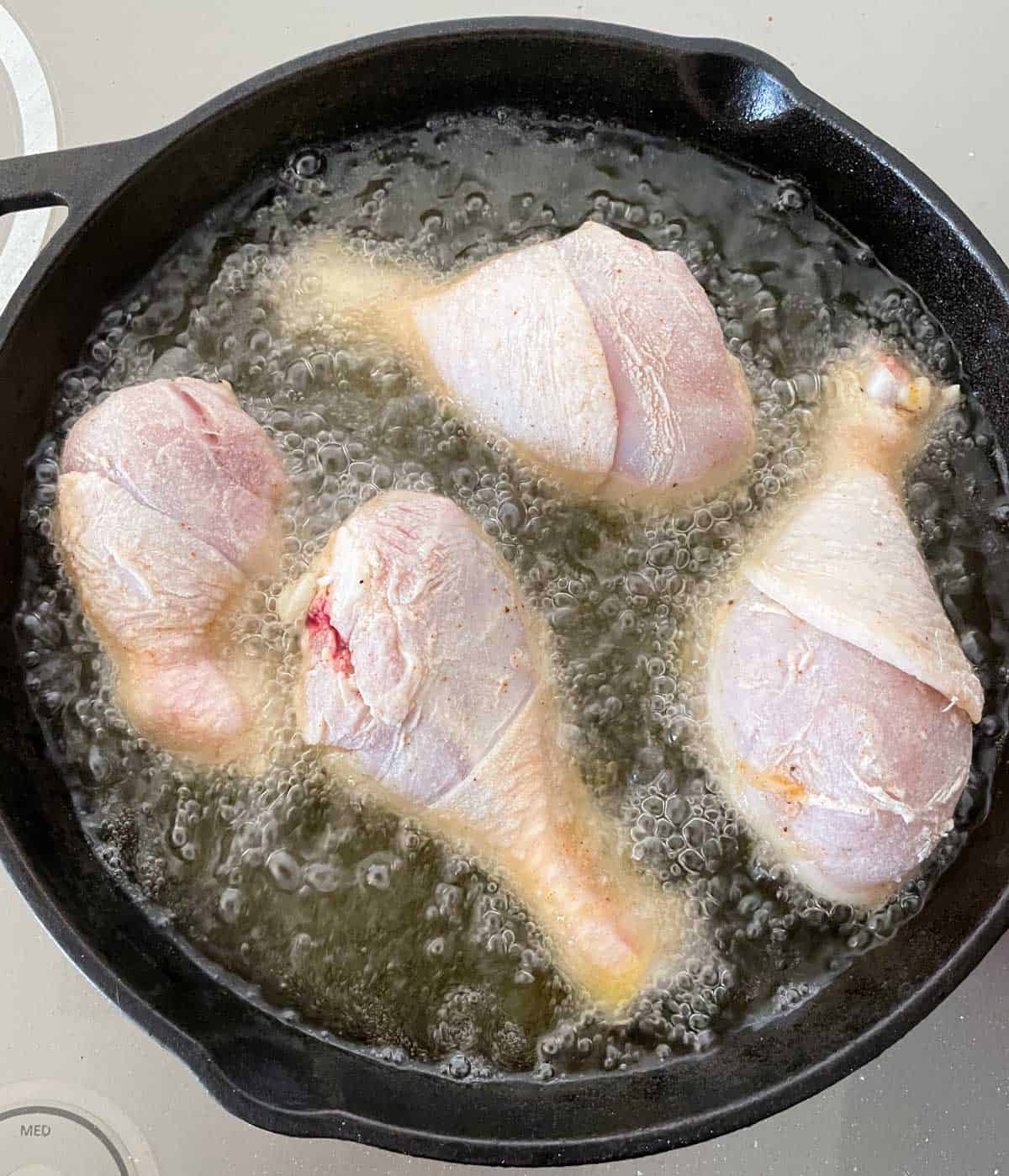 cast iron skillet frying chicken.