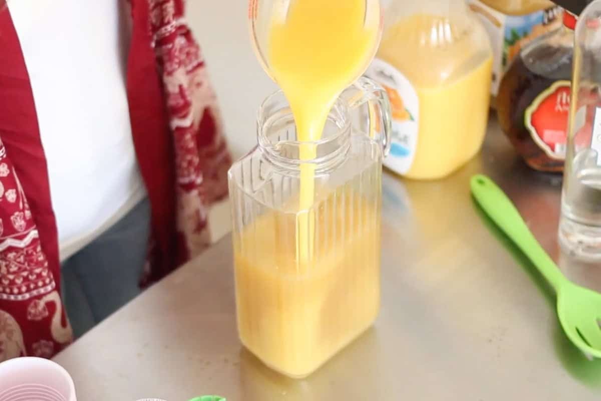 orange juice pouring into a clear pitcher.