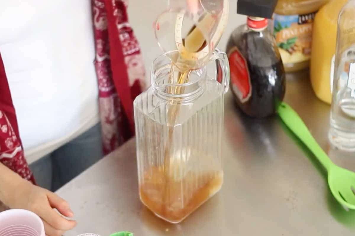 amaretto being poured into a pitcher to make yellow hammer cocktails.