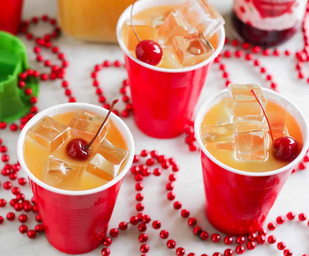 red beads on counter with yellow hammer drinks in red cups with cherries on top.