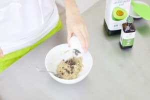 hand pouring mini chocolate chips into a bowl of cookie dough.