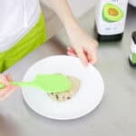 green spatula flattening a mug cookie onto a plate.