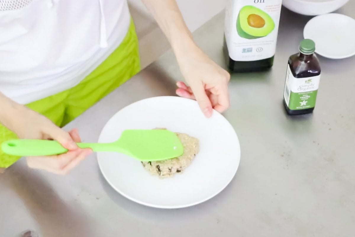 green spatula flattening a mug cookie onto a plate.