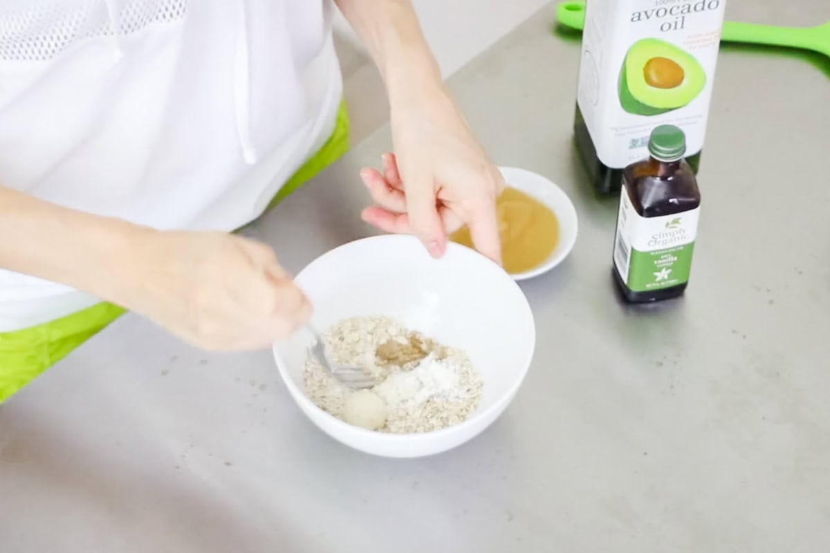 hand stirring dry ingredients into a bowl for a microwave cookie.